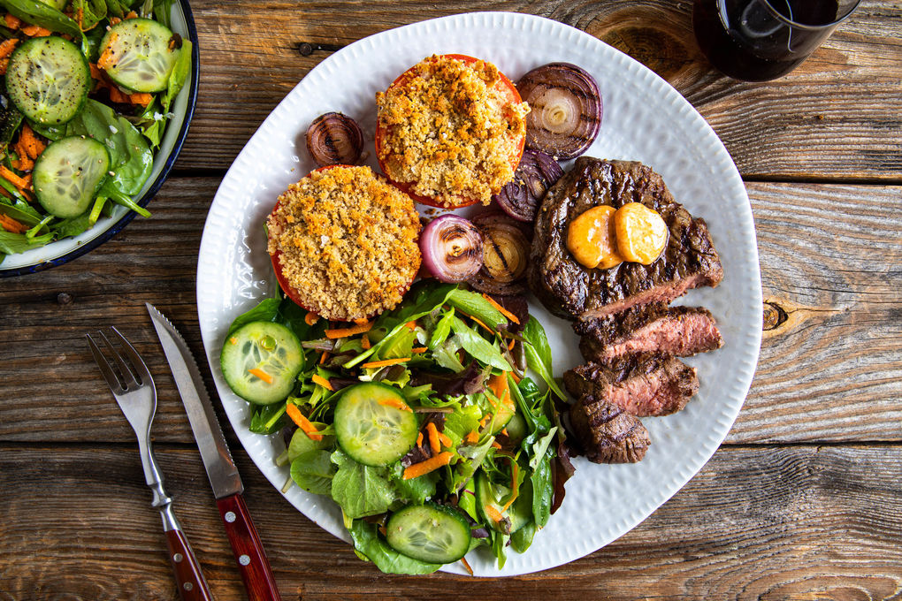 Gegrilde biefstuk met BBQ-boter en ui met gepaneerde tomaten en frisse salade