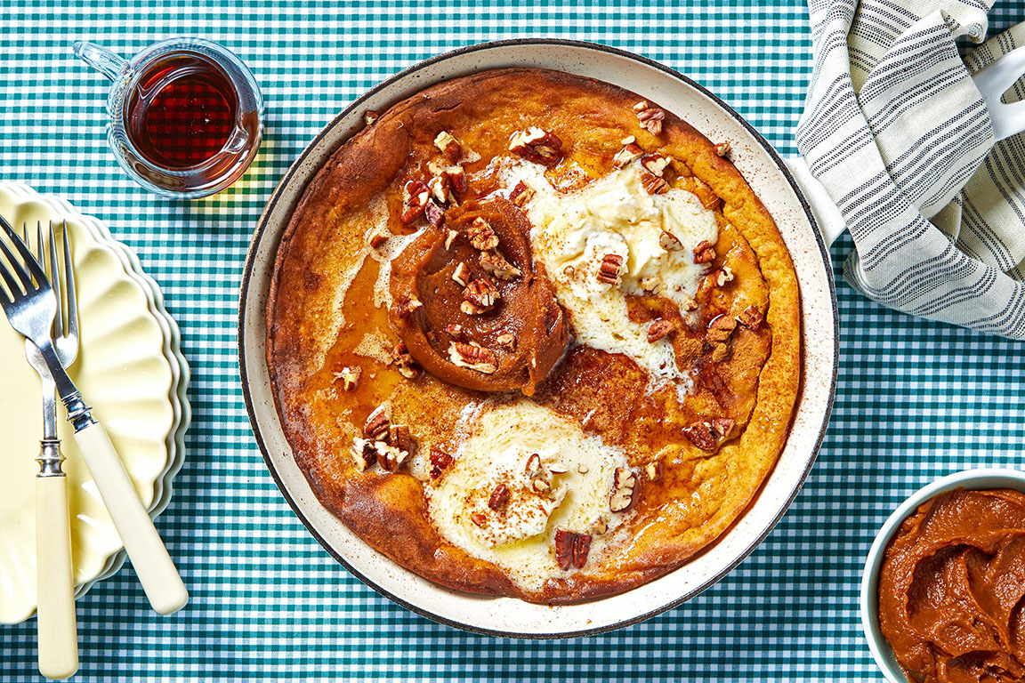 Pumpkin pie dutch baby with maple mascarpone and pumpkin butter on a blue plaid tablecloth
